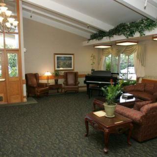 A cozy lobby with a piano, comfortable seating, and natural lighting.