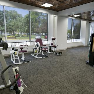 A spacious gym with various exercise machines and large windows overlooking the outdoors.