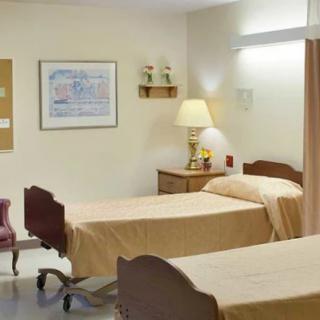 A simple hospital room with two beds and basic furnishings.