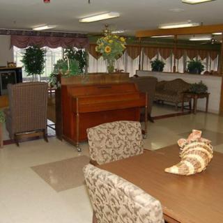 A cozy interior room with a dining area and a piano surrounded by plants and decor.