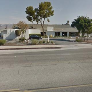A suburban street view with a commercial building and trees.