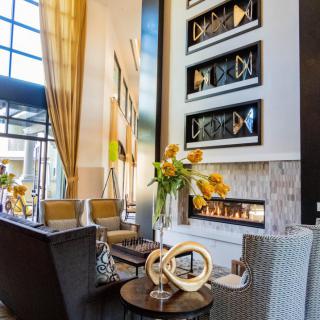 A modern living room with a luxurious seating area, featuring a fireplace and contemporary artwork.