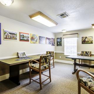 A well-lit meeting room with tables, chairs, and artwork on the walls.