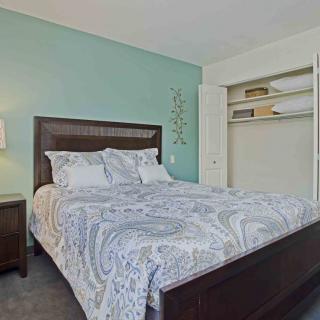 A cozy bedroom with a neatly made bed and an open closet.