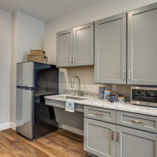 A modern kitchen with gray cabinets, a refrigerator, and a sink.