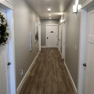 A modern hallway with wood flooring and neutral-colored walls, featuring multiple doors and stylish lighting.