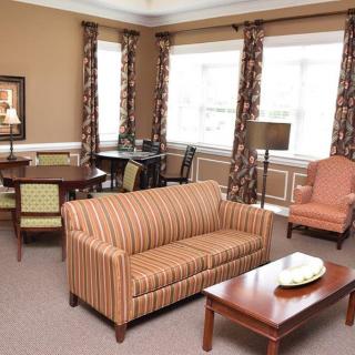 A cozy living room with a striped sofa, a coffee table, and chairs by the windows.