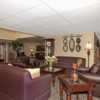 A cozy living room with leather sofas, a coffee table, and decorative elements including framed mirrors and table lamps.