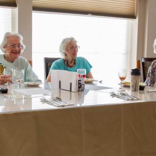 Elderly women enjoying a meal together at a dining table.