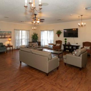 A spacious living room with elegant furnishings and decor, featuring comfortable sofas, armchairs, a coffee table, and a mounted TV.