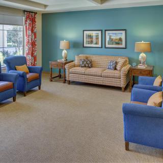 A cozy living room featuring a striped sofa, blue armchairs, and decorative table lamps.