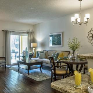 A modern living room with elegant furniture and decor, featuring a chandelier and hardwood floors.