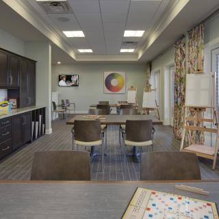 A spacious art studio set up with tables, chairs, and easels, featuring bright lighting and modern decor.