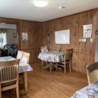 A cozy dining area with wood paneling and floral tablecloths.