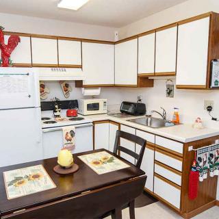 A cozy kitchen with white cabinets, a small dining table, and various appliances.