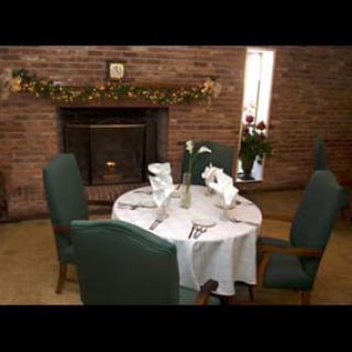 An elegantly set dining table in a cozy room with a brick fireplace.