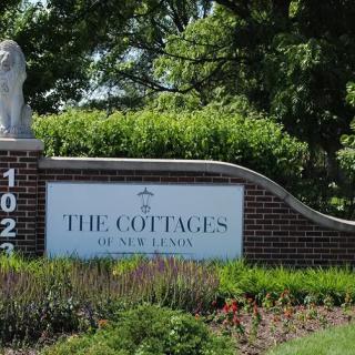 Entrance sign for The Cottages with a lion statue on top.