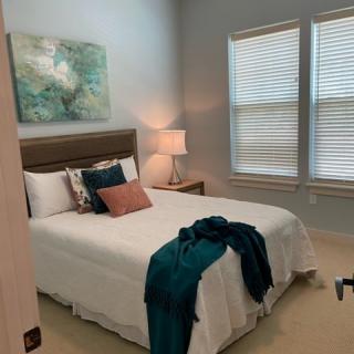 A cozy, well-decorated bedroom with a neatly made bed and soft lighting.