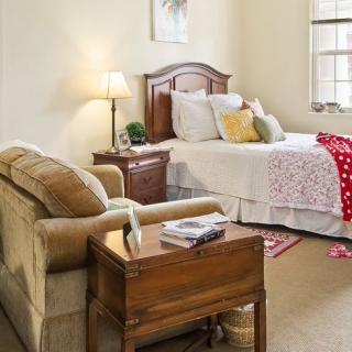 A cozy bedroom with a bed, sofa, and warm lighting.