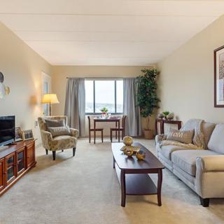 A cozy living room with a sofa, coffee table, television, and a large window with curtains.