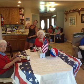 A family gathering in a kitchen and living room area with a table decorated in a patriotic, American flag theme.
