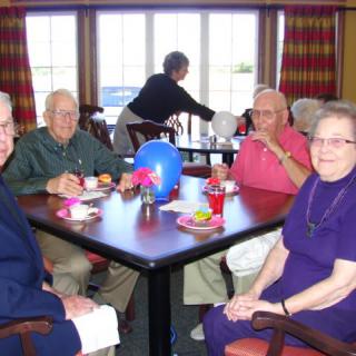 A group of seniors enjoying a meal together at a dining table.