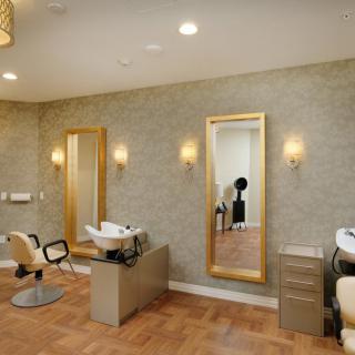 An elegant salon interior with chairs, mirrors, and warm lighting.
