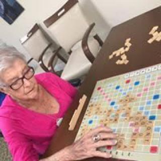 A senior woman playing Scrabble at a table indoors.