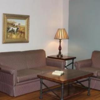 A cozy living room with a sofa, armchair, coffee table, and lamp.