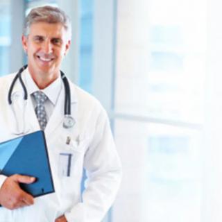 A smiling doctor holding a clipboard in a hospital setting.