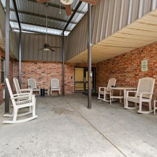 A cozy outdoor patio featuring rocking chairs and a ceiling fan, perfect for relaxation.