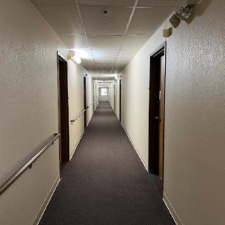 A long, well-lit hallway featuring multiple doors along the sides.
