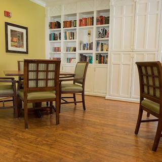 A cozy library room with a table and chairs, surrounded by bookshelves.