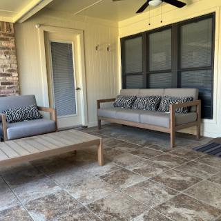 A cozy and stylish outdoor seating area featuring comfortable sofas and a coffee table.