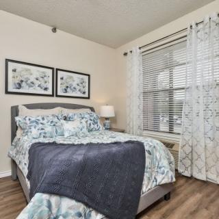 A cozy bedroom with a neatly made bed, patterned curtains, and artwork on the wall.