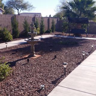 A well-maintained garden featuring a fountain, decorative stones, and pathway lighting.