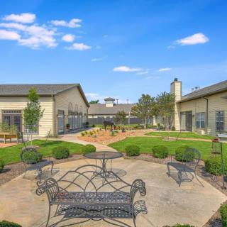 A peaceful courtyard with benches and landscaping between buildings under a clear blue sky.
