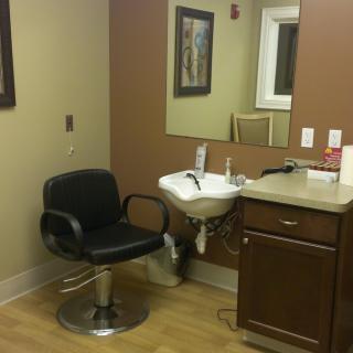 A salon setup with a chair, sink, and mirror.