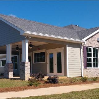 A suburban house with a front porch and well-maintained yard under a clear blue sky.