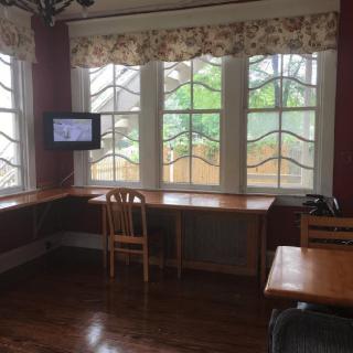 A cozy room with a desk, chair, and television by large windows.