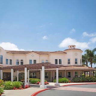 A large residential building with a welcoming entrance and a cloudy sky backdrop.