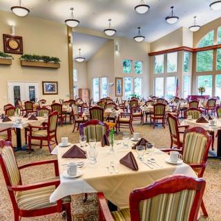An elegant dining room with neatly arranged tables and chairs, featuring large windows and tasteful decor.