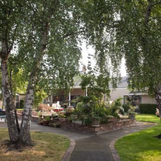 A serene garden pathway surrounded by lush trees and vibrant landscaping.