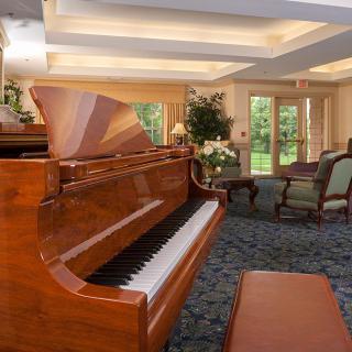 A cozy living room featuring a polished grand piano and ample natural light.