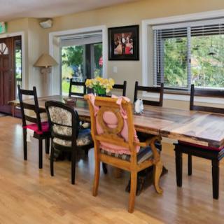 A cozy dining room with a large wooden table and an eclectic mix of chairs.
