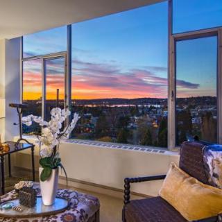 A cozy living room with a beautiful sunset view through large windows overlooking the cityscape.