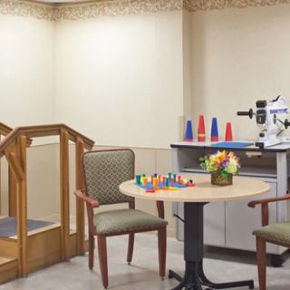 A rehabilitation therapy room with chairs, a table, stairs, and various therapy equipment.