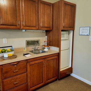 A compact kitchen with wooden cabinets, a sink, and a built-in fridge.