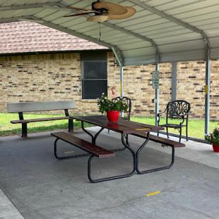 A cozy outdoor patio area featuring a table, chairs, and decorative flowers under a sheltered roof.
