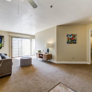A spacious living room with a sofa, ottoman, and large windows letting in natural light.